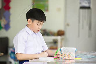 Asian kid looking at his craft at kindergarten