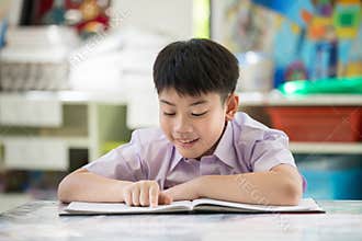 Happy asian child reading book with smile face.