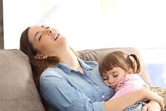 Tired mother sleeping with her baby daughter