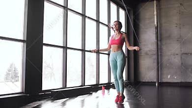 Fitness concept. Healthy lifestyle. Young slim woman jumping with skipping rope in gym. 20s 4k