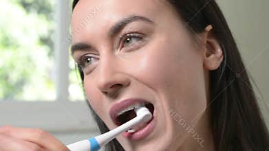 Woman In Bathroom Brushing Teeth With Electric Toothbrush