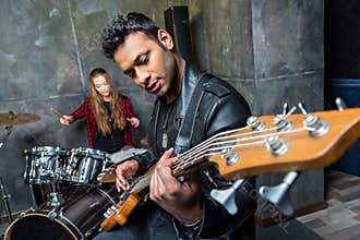 Man playing guitar with woman playing drums, rock and roll band concept