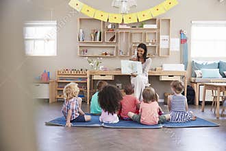Teacher At Montessori School Reading To Children At Story Time