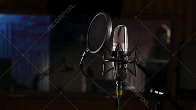 Microphone on a stand located in a music studio recording booth under low key light