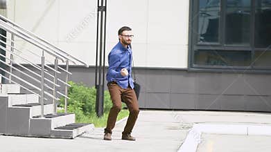 In the business center yard. The man a fast pace leaves office. The young guy very joyful jumps up on a ladder.