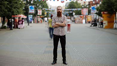 Timelapse of Young bearded man standing still at sidewalk in crowd traffic stream with people moving fast
