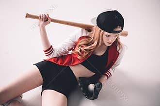 Sporty woman lying with baseball bat, glove and ball