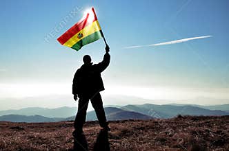 Man winner waving Bolivia flag on top of the mountain peak