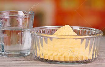 Closeup of an arepas flour inside of a cristal bowl, glas of water on wooden blcakground