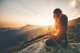Man praying at sunset mountains