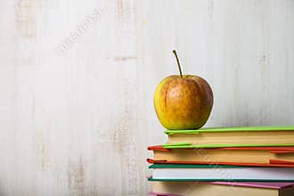Back to school. Apple on a pile of books on a light wooden table