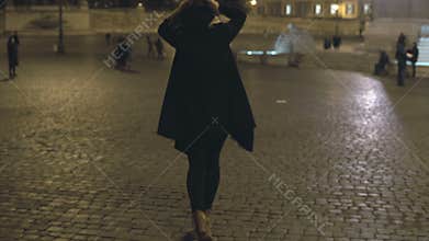Young woman walking in the evening city alone. Attractive female waiting somebody in the city centre, at the square.