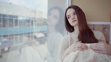 Young woman is standing and looking out the window