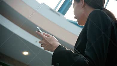 Happy young woman using smart phone in shopping mall. Businesswoman freelancer with smartphone in airport terminal