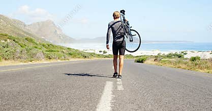 Triathlete man carrying cycle in the countryside road