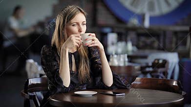 Portrait of a beautiful woman in a cafe or restaurant. A girl drinks tea or coffee and dreams about something.