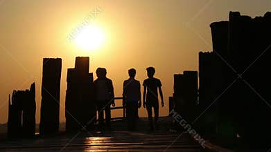 People Walking Over Wooden Bridge at Sunset 1