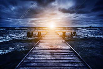 Old wooden jetty during storm on the ocean. Abstract light