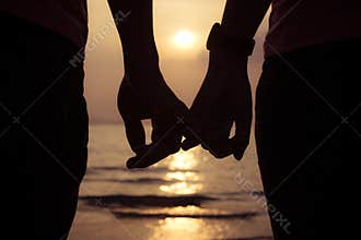 love couple holding hands fingers at sunset on the beach