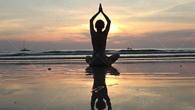 Female in yoga meditation pose at amazing sunset on the sea.