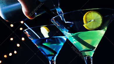 Barman pouring blue and yellow cocktail drink on a disco bar table, disco atmosphere