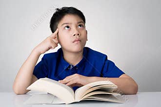 Little asian boy read a book and think about that