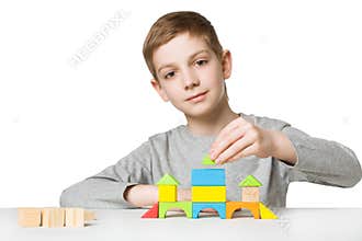 Portrait of a boy building house of wooden blocks