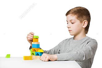Boy building house made of wooden blocks