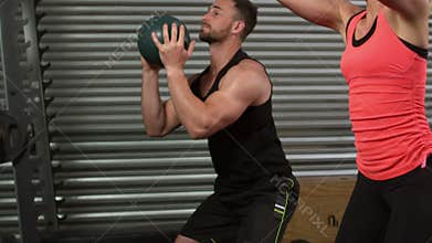 Muscular couple doing ball exercise