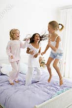 Three Young Girls Jumping On A Bed