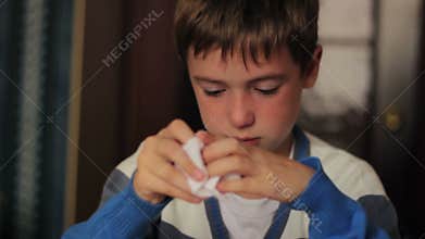 Sick boy blowing his nose into a napkin while
