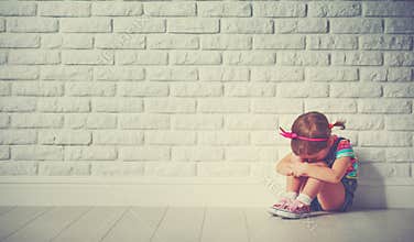 Little child girl crying and sad about brick wall
