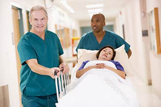 Two Orderlies Pushing A Woman Down A Corridor