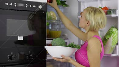 Woman hold bowl take raw fresh vegetables from