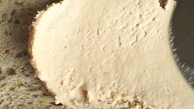 Macro video of butter being spread on bread, view from above