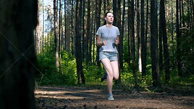 Runner woman running in park exercising outdoors fitness tracker wearable technology girl running in the woods in the