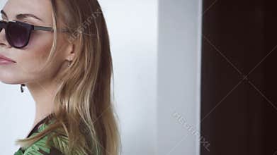 Glamour beautiful woman wearing black swimwear, floral long shirt and sunglasses walking out of ladys restroom - slow motion video