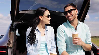 Happy couple with coffee at hatchback car trunk 11