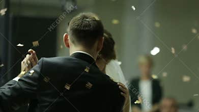 Beautiful brunette bride and handsome groom dancing first dance at the wedding party. Confetti in the air. Very tender