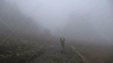 Hiker with backpack in the mountains fog