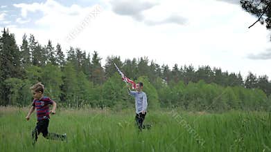 Two boys run across the meadow with US flag