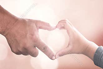 Adult and Child Hands Forming Heart Shape against Soft Warm Bokeh Background