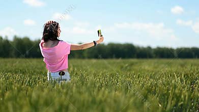 Young woman making selfies in green wheat field