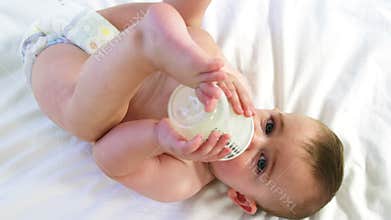 A baby is drinking his feeding bottle