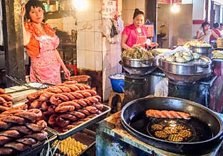 Two street vendors are selling Chinese traditional food in an open market in China