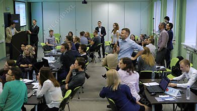 Many people in the room sitting together at the tables and participating in the process of teambuilding. Men and women