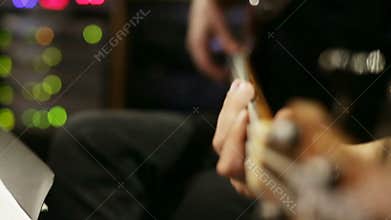 Close-up view on guitar playing. Focus onHand