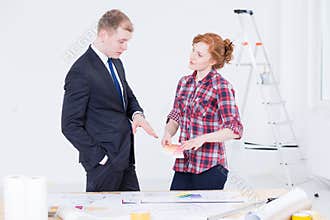 Elegant man in suit and a woman standing close to the drafting table