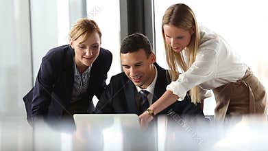 Group of business people looking at laptop and discussing