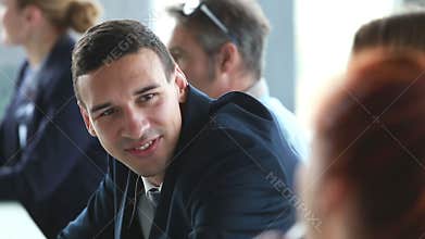 Handsome businessman talking with female colleagues at conference table